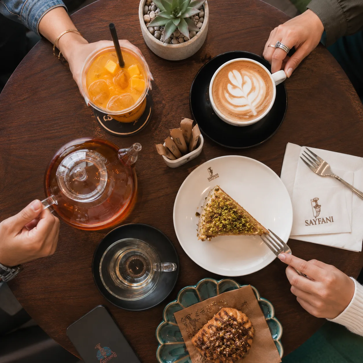 Overhead view of drinks and pastries shared by friends at Sayfani